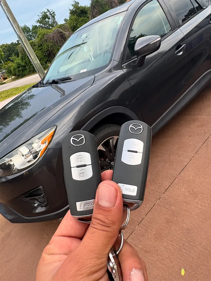 Two programmed Mazda smart keys held in front of a gray Mazda SUV in Palm Coast, FL